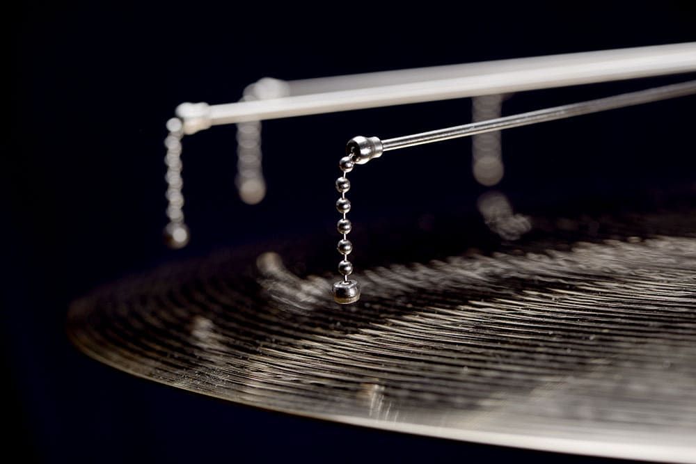 Close up view of one Jaspercussion Cymb Siz sizzler chain suspended above the edge of a ride cymbal.