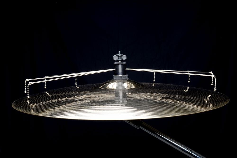 Side view of a ride cymbal with a dark background, with an attached Jaspercussion Cymb Siz adjustable cymbal sizzler in upright position.